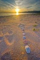 An arrow formed from stones points the way towards a stunning sunset along the beach in Agawa Bay, part of Lake Superior Provincial Park in Ontario, Canada.