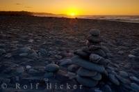 Sunset brings a close to another day at Gillespies Beach on the South Island of New Zealand as people have used the perfectly shaped rocks for building cairns.