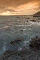 The water swirls around the rocks of Cape Palliser during sunset on the North Island of New Zealand.