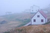 Battle Island in Southern Labrador, Canada is barely visible on this foggy evening except for a few of the historic buildings like the cookhouse/bunkhouse and the Battle Harbour Inn.