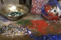 The molten glass is rolled in small beads of color glass and then sculpted into an art piece.