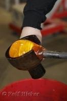 An artist uses a special sculpting tool to shape the molten glass at the Lincoln City Glass Center in Oregon, USA.