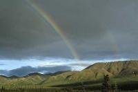 A double rainbow forms over the landscape of the Alaska Range in Denali National Park of Alaska, USA.