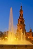 This lit fountain at dusk can be found in the Maria Luisa Park (Parque Maria Luisa) at the Plaza de Espana in Seville, Spain.