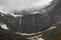 The Milford Road at Homer Saddle in Fiordland National Park is surrounded by steep mountain cliffs over which newly formed waterfalls cascade over during heavy rainfall.