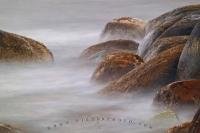 Long exposure photo of a ocean wave crashing against rocks