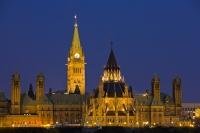 The lights come on at Parliament Hill at dusk in Ottawa Ontario, as seen here in this view from Nepean Point. This is a hill overlooking the Parliament Buildings and other attractions located in downtown Ottawa.