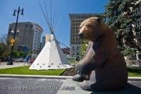 A statue entitled 'The Pondering Grizzly' by Canadian artist Clarence Tillenius, part of the Manitoba-wide 'Bears on Broadway' collection, stands outside the City Hall with a teepee in Winnipeg Manitoba Canada.