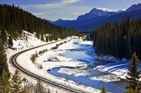 This beautiful winter landscape is in Banff National Park with the winding railway tracks which run along side the icy Bow River towards the majestic Canadian Rocky Mountains.