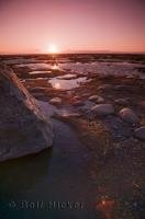 The sunsets are electric along the shores of the Sainte Lawrence River in Quebec, Canada especially when low tide reveals small pools and large rocks.