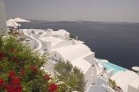 Whitewashed buildings cling to the rim of the caldera while overlooking the crater and the Aegean Sea.