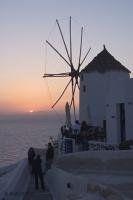 An image of a windmill at a small restaurant in Santorini with views of the setting sun over the Aegean Sea.