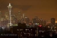 The Seattle city lights reflect in the cloudy Washington night sky.