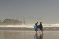 A couple of surfer boys heading out to catch some waves at Piha Beach near Auckland New Zealand