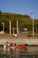 The Canadian Coast Guard cruise the waters in front of the totem poles of the Namgis Burial Grounds in Alert Bay, BC, Canada.