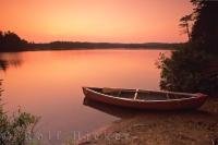 A canoe pulled up on the shores of Algonquin Lake in Ontario, Canada as sunset alters the colors of the world as we know it.