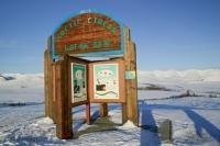 Photo of the wooden arctic circle sign along the Dempster Highway in winter in the Yukon Territory, Canada.