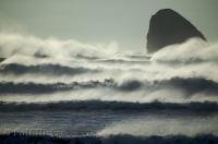 Cape Meares beach with huge waves rolling into and crashing against rocky outcrops along the Oregon Coast, USA.