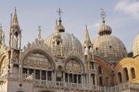 The exterior of the beautiful Basilica di San Marco showing the ornate arches and two of the five domes in Venice, Italy.