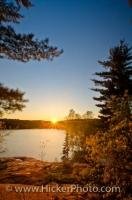 The sun just dips behind George Lake in Killarney Provincial Park and for a moment it is a bright ball of light turning the surrounding scenery to a beautiful yellow and orange colour and making the entire lake sparkle with light.