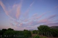 Wisps of pink and white clouds scatter above the village of Benidoleig, Valencia in Spain Europe at sunset.