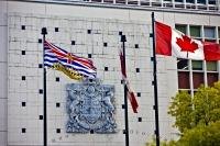 The vibrant colours of the British Columbia Flag stand out as it waves in wind beside the national flag of Canada.