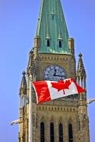 The distinctive red and white Canadian Flag, bearing a stylized maple leaf, flies proudly in front of the Peace Tower on Parliament Hill in Ottawa, Ontario.