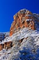 A picture showing the beautiful contrast of white snow and red rock against a vivid blue sky in the Oak Creek Canyon during the winter months in Arizona, USA.
