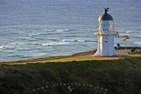 On this day, a few people stand around the base of the Cape Reinga Lighthouse on the North Island of New Zealand admiring the scenery.