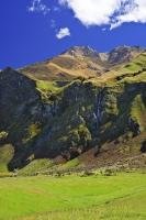 A view showing a mixture of arid mountain scenery on Treble Cone and lush green farmland in Central Otago on the South Island of New Zealand.