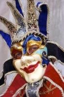 A costumed and masked character smiles into the camera beside the Grand Canal in Venice, Italy. Carnival season in Venice is an annual event and people dress in these elaborate costumes and masks and party in this city on water.