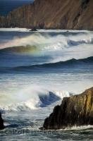 The view of beautiful ocean waves with tips clad in a colorful rainbow seen from the Ecola State Park in Oregon, USA.