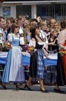 The European women are adorned in dirndls, a traditional Bavarian dress in Germany.