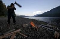 Tourist at work chopping firewood for a campfire at Nimpkish Lake outside of Port McNeill in British Columbia.