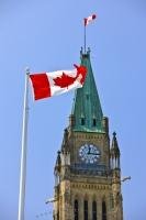 A large Canadian National Flag waves in the breeze in front of the Peace Tower at Parliament Hill in Ottawa Canada.