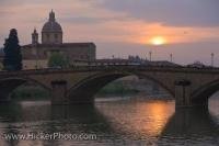 As sunset takes over the sky in the City of Florence, Tuscany in Italy, Europe, the bridge known as Ponte alla Carraia and the Arno River sparkle in the light.