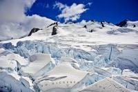 At the summit of the Fox Glacier on the South Island of New Zealand, the scenery is stunning as the sunlight reflects off the snow and ice under the deep blue colored sky.
