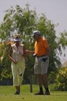 A man has a golf strategy for his partner at the Oliva Nova Beach and Golf Resort on the Costa Blanca, Valencia in Spain as she prepares to tee off.
