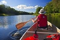 A canoer leisurely paddles down the scenic Mersey River, one of the many serene waterways located in the great outdoors of Kejimkujik National Park and National Historic Site in Nova Scotia, Canada.