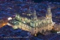 This sixteenth century cathedral that is lit up at dusk is the Jean Cathedral Church Building located in the Province of Jaen in Andalusia, Spain. The bright white lights make this building stand out against the darkened streets around.