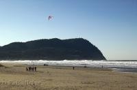 People on the beach in Seaside, Oregon, some flying a kite and others walking along the beach.