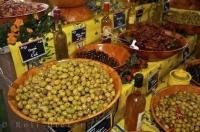 A large selection of marinated black and green olives, and sun dried tomatoes on display on the tables at the weekly market held in the quaint village of Moustiers Ste Marie in the Provence region of France.