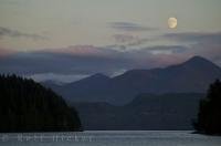 The moon is getting ready for bed as the sun rises in Nootka Sound on the West Coast of Vancouver Island in British Columbia.