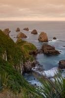 Rocks or nuggets arise from the waters beyond Nugget Point along the Southern Scenic Route in Otago, New Zealand.