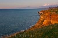 A west coast sunset lights up the ocean cliffs of Taranaki on the North Island of New Zealand.