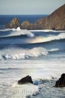 Large, rainbow tipped waves roll in from the Pacific Ocean along the Oregon Coast, USA.