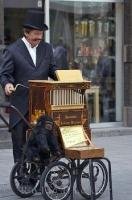 An organ grinder tours the streets of downtown Vienna, Austria playing his music for all the passing people.