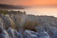 The sun sets over the Tasman Sea and the Pancake Rocks in Paparoa National Park on the West Coast of New Zealand.