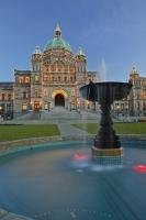 The path leading around the pool of a fountain in the parliament grounds leads off towards the British Columbia Parliament buildings which are illuminated by thousands of small lights.