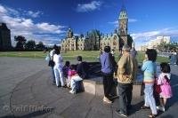 Under the blue sky of Ottawa, Ontario visitors take pictures of the Parliament building atop Parliament Hill.
